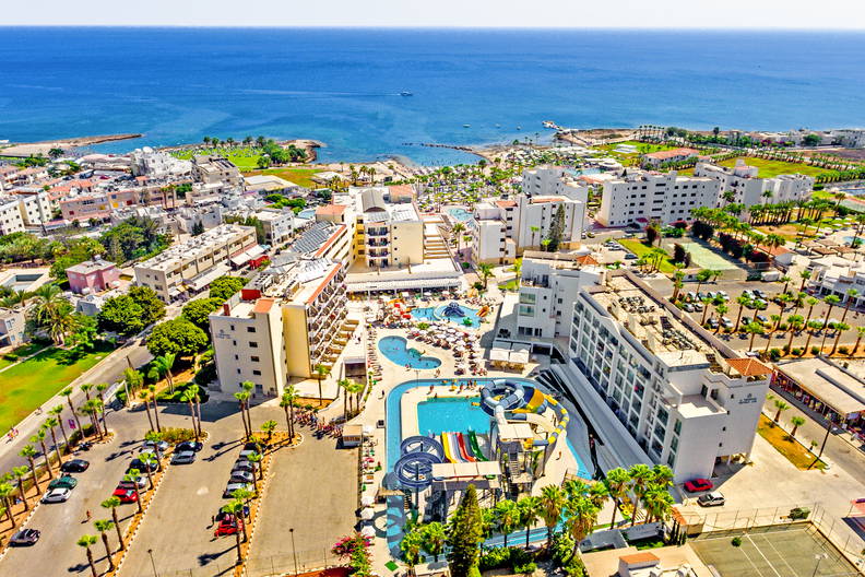 Widok z lotu ptaka na nadmorski kompleks hotelowy z basenami i kolorowym aquaparkiem.