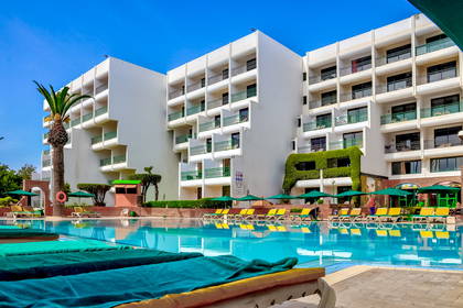 Basen hotelowy z leżakami i parasolami.