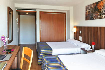Pokój hotelowy z dwoma łóżkami, biurkiem i szafą.