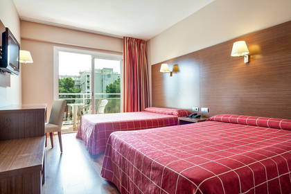 Pokój hotelowy z dwoma łóżkami, biurkiem i balkonem.