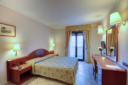 Pokój hotelowy z łóżkiem, biurkiem i balkonem.