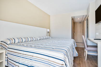 Pokój hotelowy z łóżkiem w paski i biurkiem do pracy.