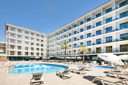 Kompleks hotelowy z basenem, leżakami i palmami w słoneczny dzień.
