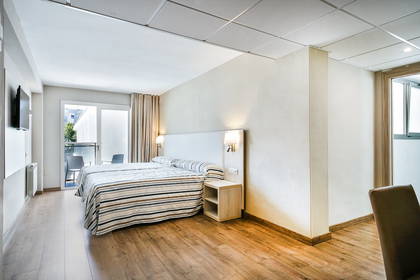 Pokój hotelowy z łóżkiem, balkonem i drewnianą podłogą.