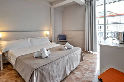 Pokój hotelowy z łóżkiem, ręcznikami i szampanem w wiaderku z lodem.