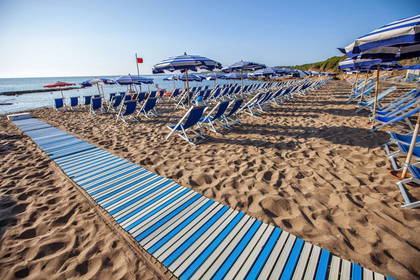 Plaża z leżakami i parasolami w biało-niebieskie pasy.