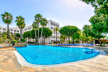 Hotelowy basen z palmami i leżakami.