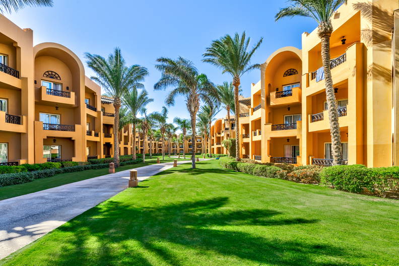 Ośrodek wypoczynkowy z pomarańczowymi budynkami i palmami.