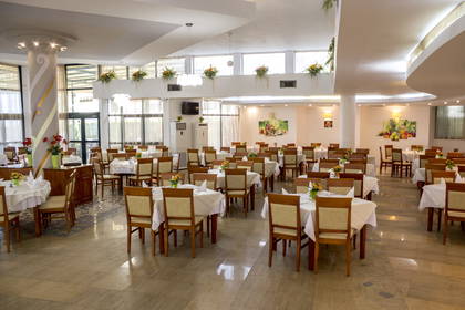 Wnętrze restauracji z nakrytymi stołami i krzesłami.