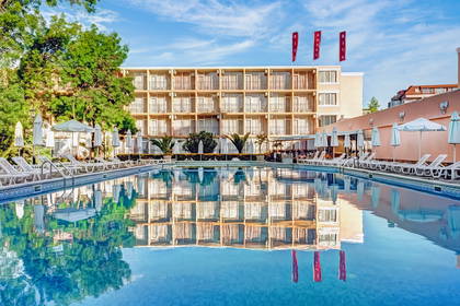 Basen z leżakami i parasolami przy Hotelu Riva.