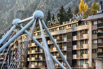 Nowoczesny most linowy i budynek hotelu w tle.