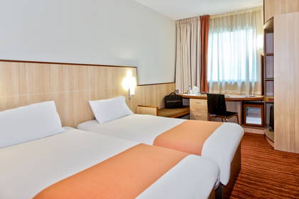 Pokój hotelowy z dwoma łóżkami, biurkiem i krzesłem.