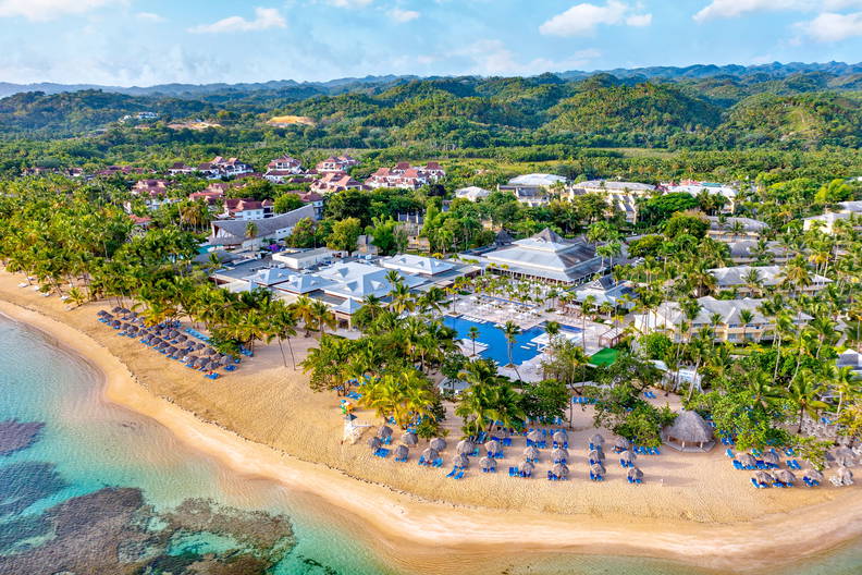 Resort wypoczynkowy z plażą, widok z lotu ptaka. W tle zielone wzgórza.