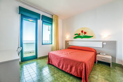 Pokój hotelowy z łóżkiem, balkonem i kwiatami na ścianie.