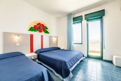 Pokój hotelowy z dwoma łóżkami, oknem i balkonem.