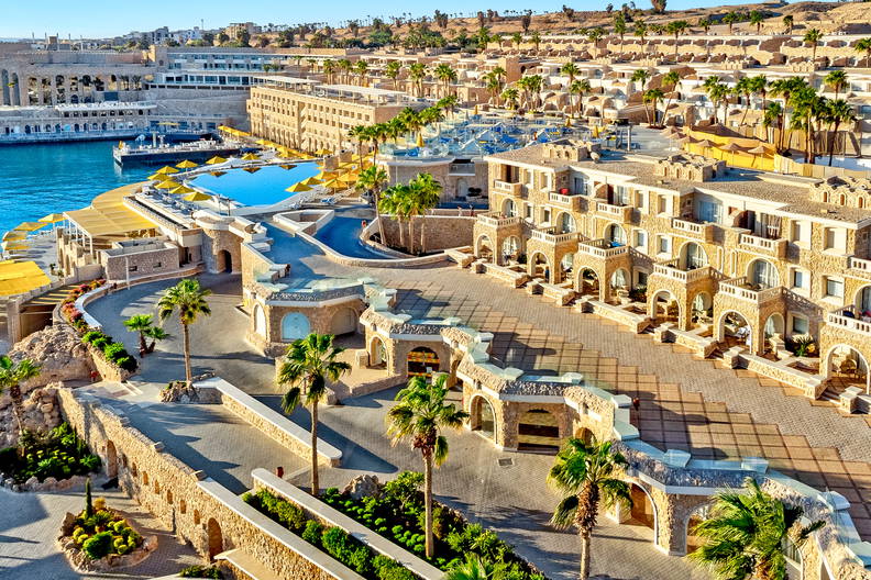 Kompleks hotelowy z basenami i palmami, widok z góry.