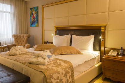 Pokój hotelowy z dużym łóżkiem, fotelami i szlafrokami.