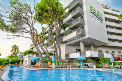 Hotel Park z basenem otoczonym leżakami i zielenią.