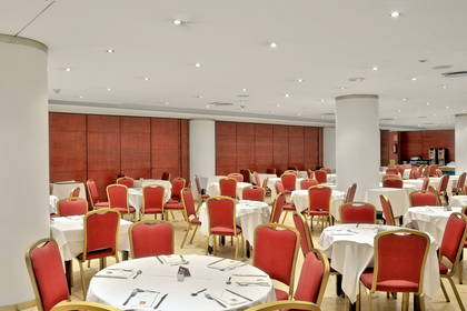 Sala restauracyjna z nakrytymi stołami i czerwonymi krzesłami.