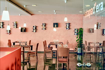 Restauracja z ustawionymi stolikami i ścianą dekoracyjną z butelek wina.