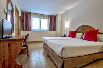 Pokój hotelowy z dwoma łóżkami i drewnianym biurkiem.