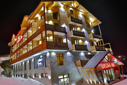 Wielopiętrowy hotel z balkonami oświetlony nocą.