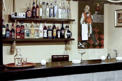 Bar z drewnianą ladą i półkami pełnymi alkoholu.
