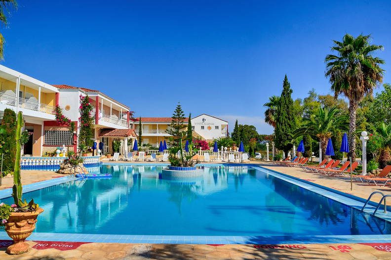 Kompleks hotelowy z basenem w słoneczny dzień.