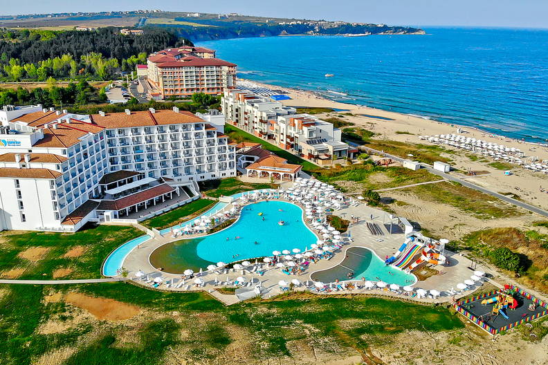 Zdjęcie lotnicze nadmorskiego kurortu z basenami, plażą i hotelami.
