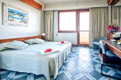 Pokój hotelowy z balkonem, łóżkiem i niebieską podłogą.