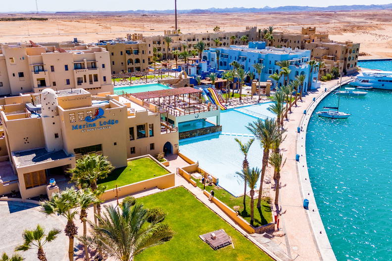 Kurort nad wodą z basenami, palmami i jachtami z lotu ptaka.