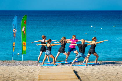 Grupa osób ćwiczy jogę na plaży.