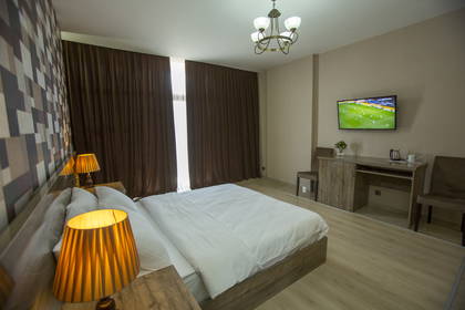 Pokój hotelowy z łóżkiem, telewizorem i biurkiem.