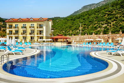Hotel z basenem na tle gór.