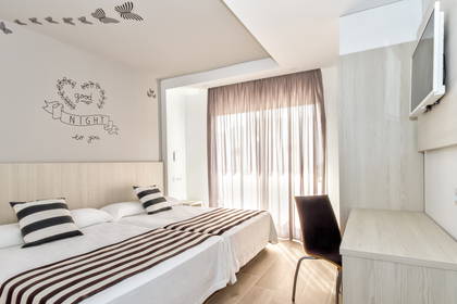 Pokój hotelowy z dwoma łóżkami i biurkiem do pracy.
