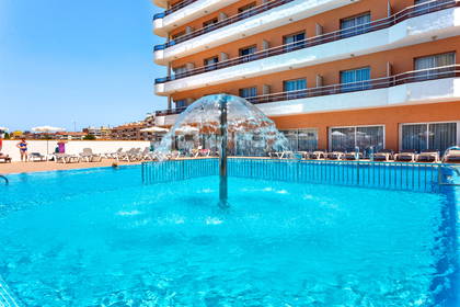 Basen hotelowy z fontanną i leżakami.