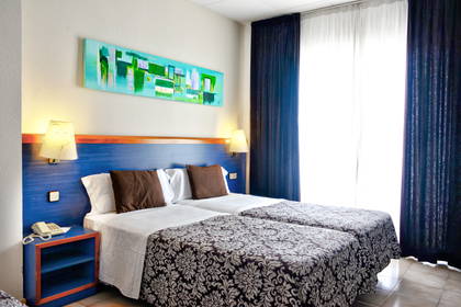 Pokój hotelowy z dwoma łóżkami i niebieskim zagłówkiem.