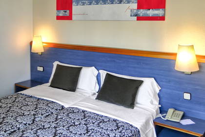 Pokój hotelowy z dwoma łóżkami, lampkami i telefonem.