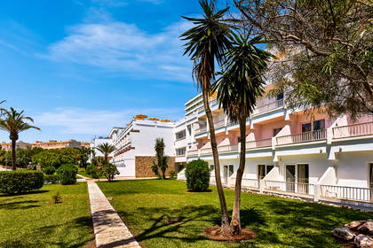 Hotel z palmami i zielonym trawnikiem.