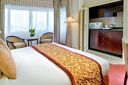 Pokój hotelowy z łóżkiem, aneksem kuchennym i częścią wypoczynkową.