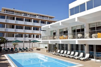 Kompleks hotelowy z basenem, leżakami i parasolami.