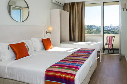 Pokój hotelowy z balkonem i widokiem na miasto. Widoczne łóżka.