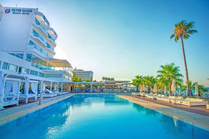 Hotel Silver Sands z basenem, leżakami i palmami.