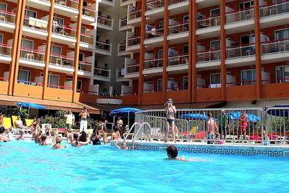 Ludzie relaksują się w basenie hotelowym w słoneczny dzień.