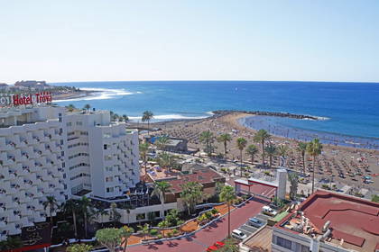 Hotel Troya i plaża z palmami w tle.