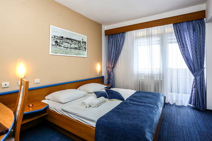 Pokój hotelowy z łóżkiem, zasłonami i oknem.