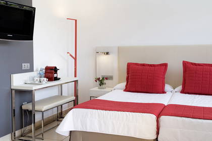 Pokój hotelowy z dwoma łóżkami i stolikiem nocnym.