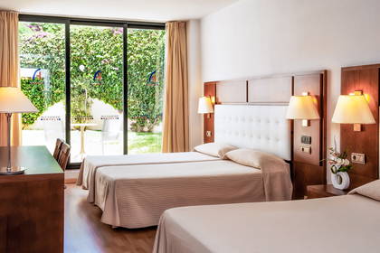 Pokój hotelowy z dwoma łóżkami i widokiem na ogród.