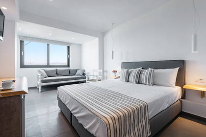 Jasny pokój hotelowy z łóżkiem, sofą i dużym oknem.