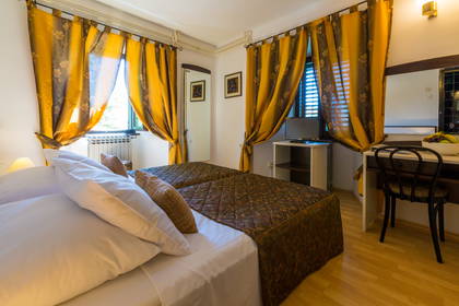 Pokój hotelowy z dwoma łóżkami i zasłoniętymi oknami.
